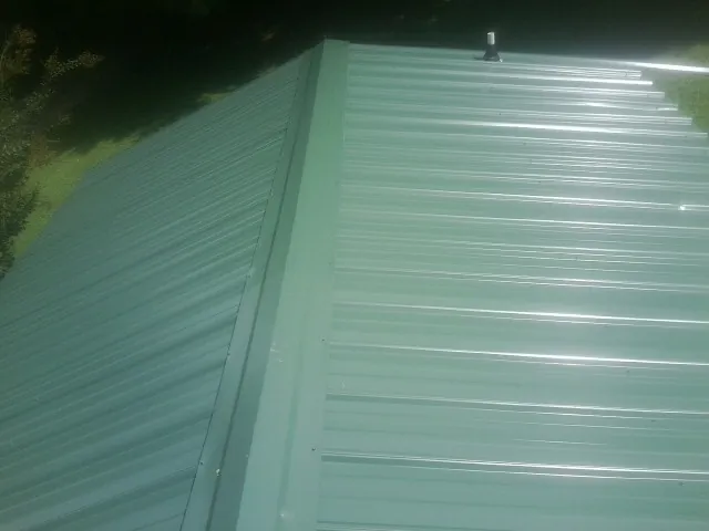New green metal panels meeting at the ridge of a roof — Flat Roof Repair work by our crew in South Milford