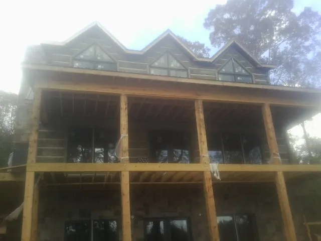 Dormers and porch framing on a large log home under construction — Roof Coating work by our crew in South Milford