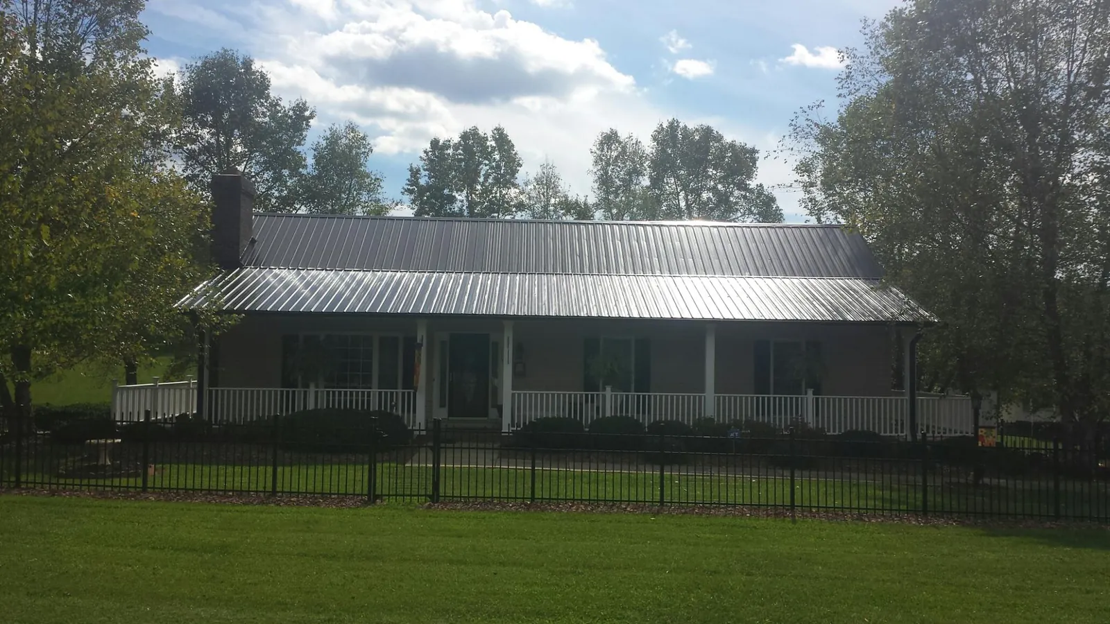 Gray metal roof on a brick ranch with a full width front porch — Gutter Guard Installation work by our crew in South Milford
