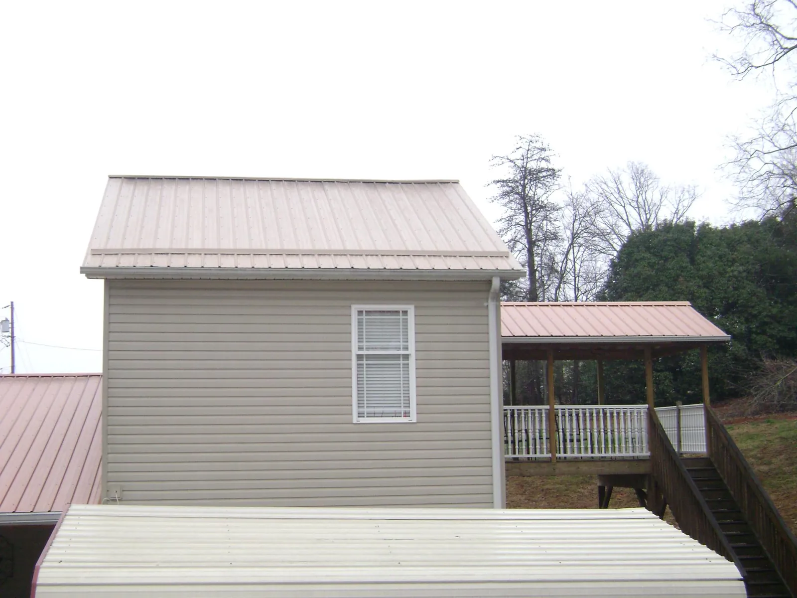 Tan metal roofs on a two story addition and attached porch, from a Roof Replacement job in South Milford